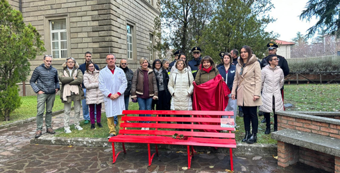 inaugurazione della panchina rossa con una rosa rossa poggiata sopra e un gruppo di persone dietro di essa